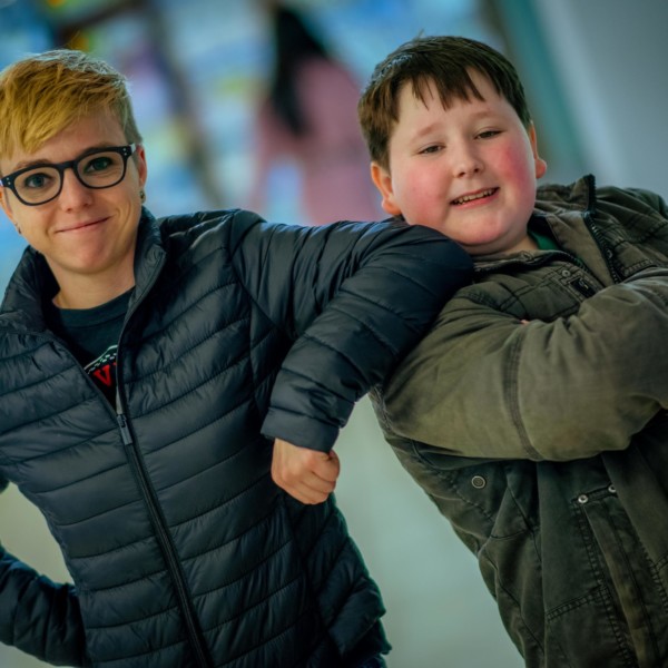 two people smiling at camera leaning on each other